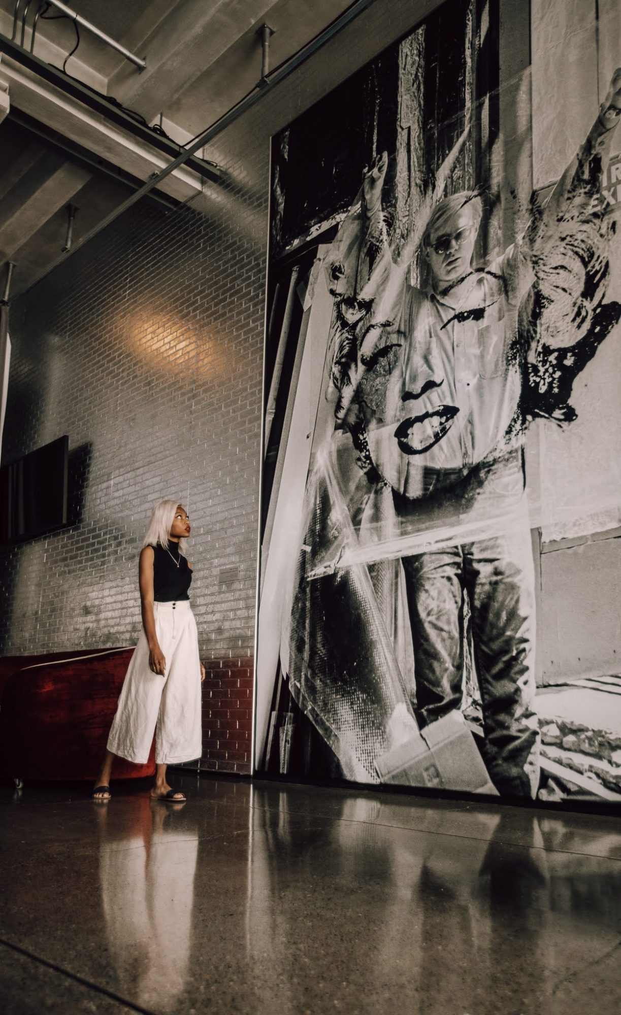 woman standing in front of a large piece of artwork by Andy Warhol