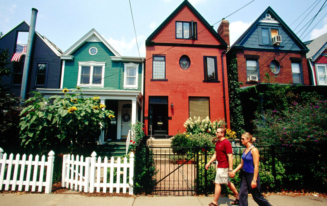 pittsburgh housing market, man and woman holding hands walking by a row of historic pittsburgh homes

