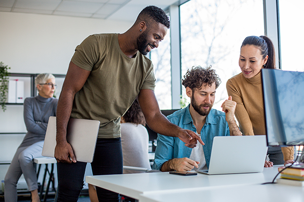 Group of coworkers huddled around a laptop 