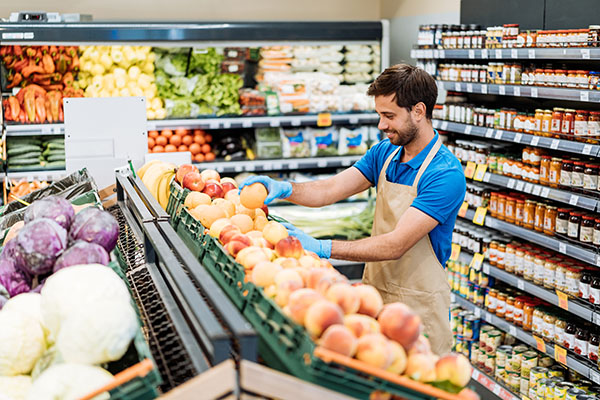 An employee stacking fruit in a supermarket