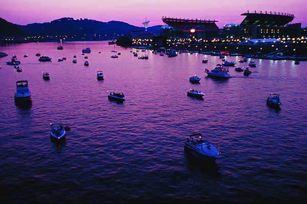 Boats on a river in Pittsburgh during dusk