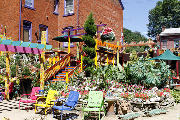 Colorful chairs surrounded by blooming plants in Randyland during the summer