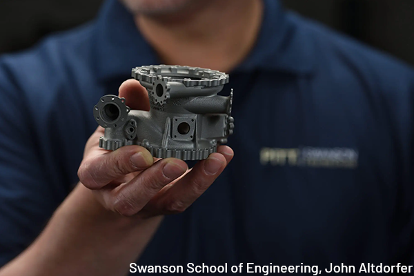 An engineering student holding a manufacturing piece at the Swanson School of Engineering,