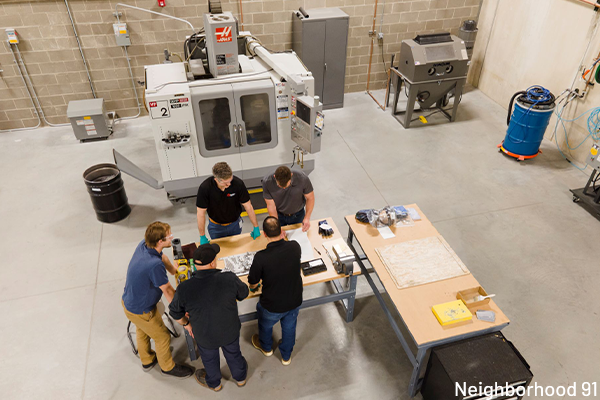 Aerial of additive manufacturers gathered around a lab table.