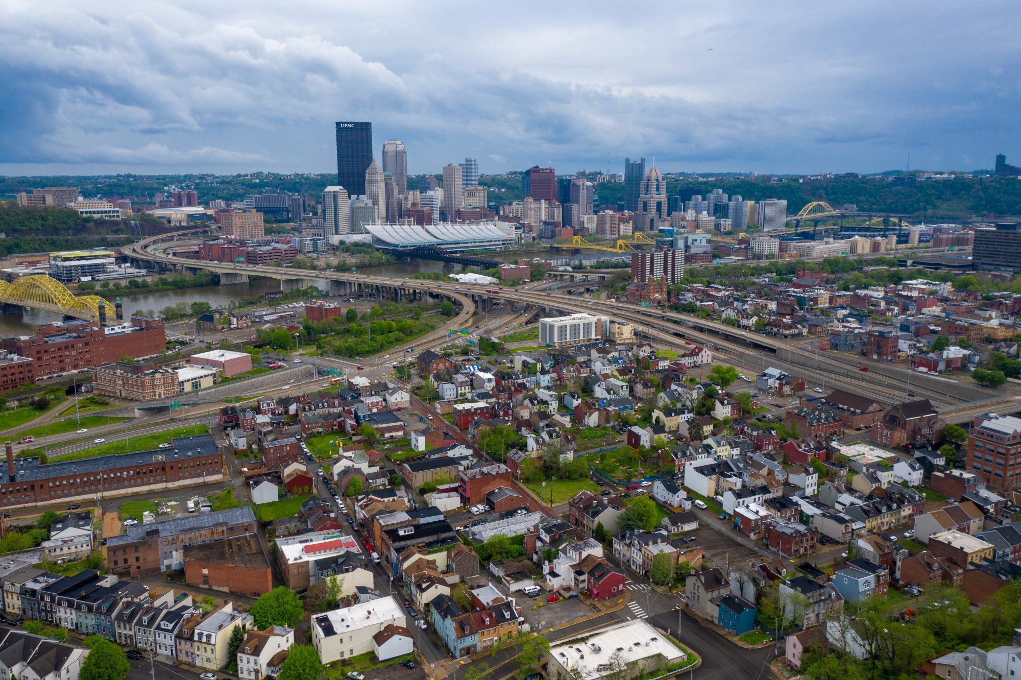 An overhead photo of a neighborhood outside of Downtown Pittsburgh with the city outline in the background.