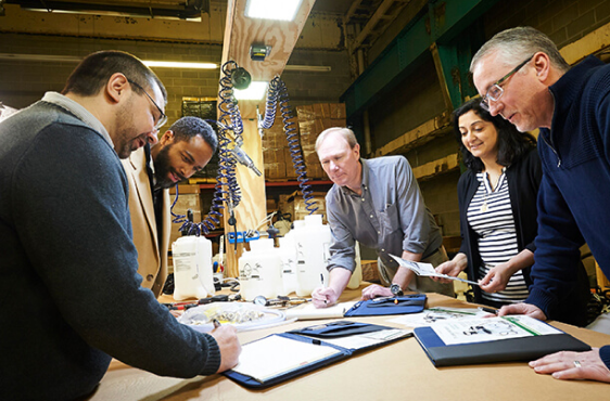 Diverse group of people standing around a table reviewing documents